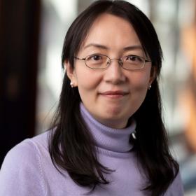 A dark-haired woman in a purple turtleneck